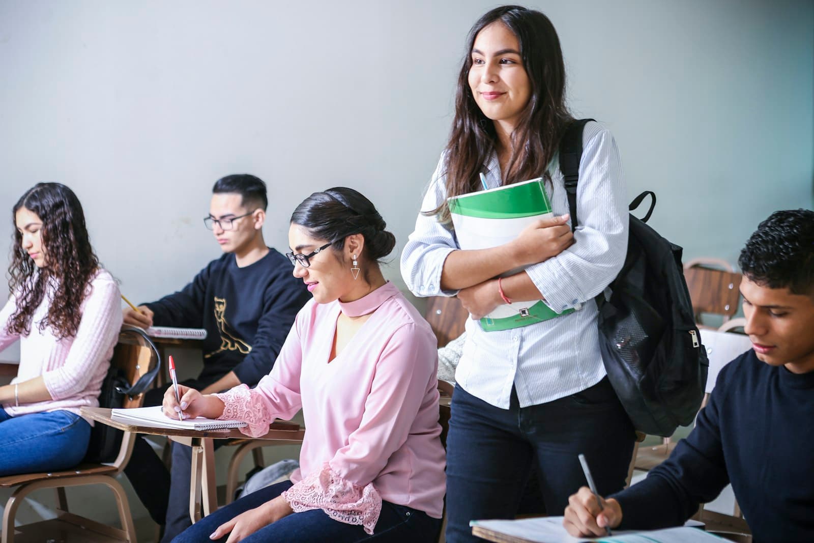 A student smiling in class, holding a notebook